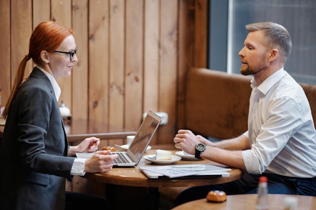 a-man-and-a-woman-having-a-business-discussion-at-a-caf-table-with-a-laptop-and-documents a-man-and-a-woman-having-a-business-discussion-at-a-caf-table-with-a-laptop-and-documents