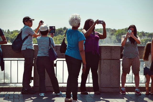 People standing on a bridge taking pictures of themselves and the water behind them in the daytime
